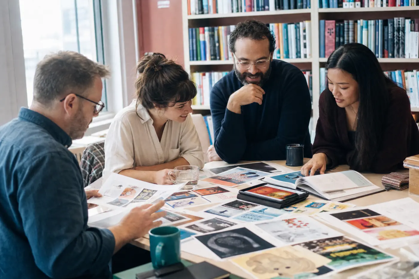 A trade publishing team planning a season around a table covered with cover proofs