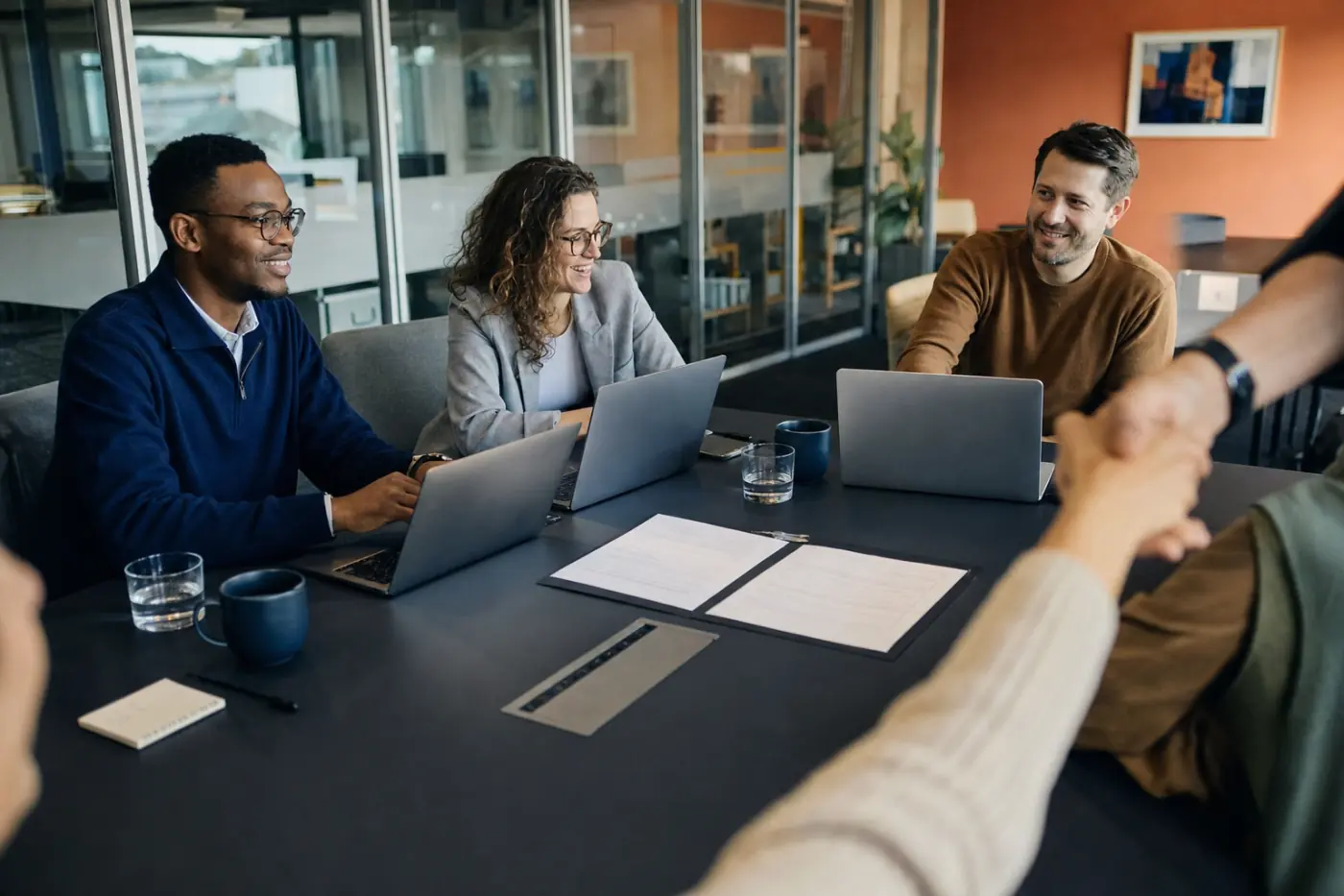 Four people from two organisations around a meeting table, a partnership agreement between them